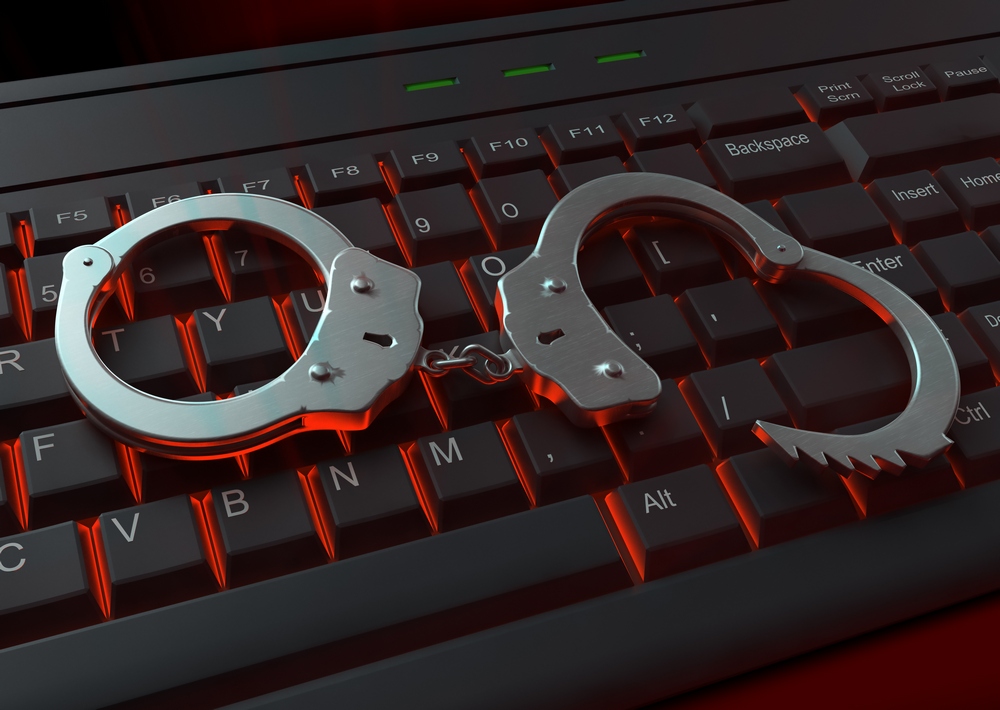 Handculfs on a red lit keyboard Internet crime concept illustration